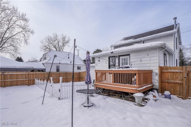 snow covered house with a wooden deck