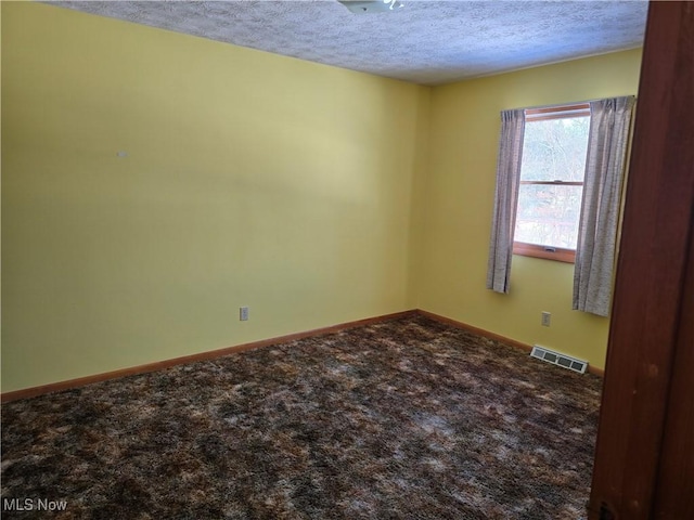 carpeted empty room featuring a textured ceiling