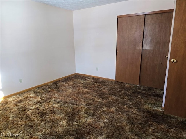 unfurnished bedroom featuring a closet and dark colored carpet