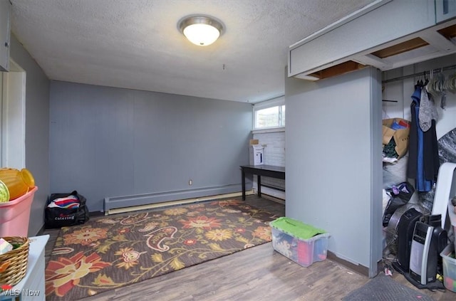 basement with hardwood / wood-style floors, baseboard heating, and a textured ceiling