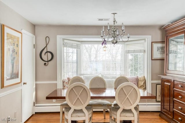 dining area with a wealth of natural light, light hardwood / wood-style flooring, and an inviting chandelier