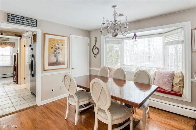 dining area with a baseboard heating unit, light hardwood / wood-style flooring, and a chandelier