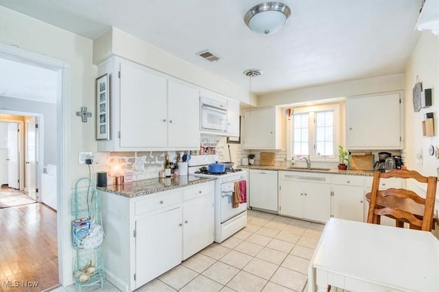 kitchen featuring sink, backsplash, white cabinetry, light tile patterned flooring, and white appliances