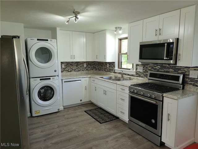 kitchen featuring sink, white cabinetry, appliances with stainless steel finishes, and stacked washing maching and dryer