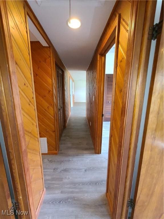 hall featuring wooden walls and light hardwood / wood-style floors