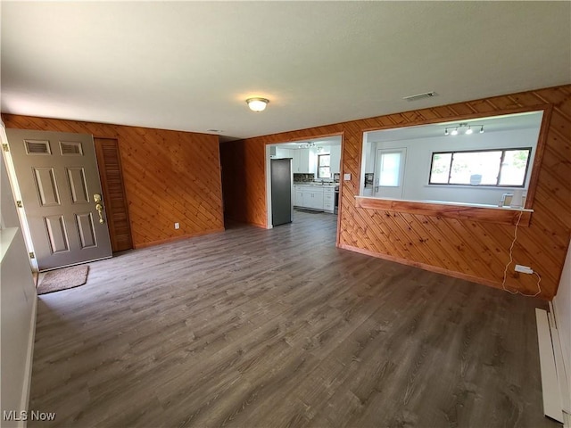 unfurnished living room featuring wooden walls and dark wood-type flooring