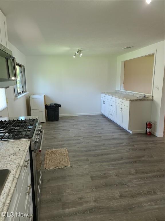 kitchen with white cabinets, gas range, light stone countertops, and dark hardwood / wood-style flooring