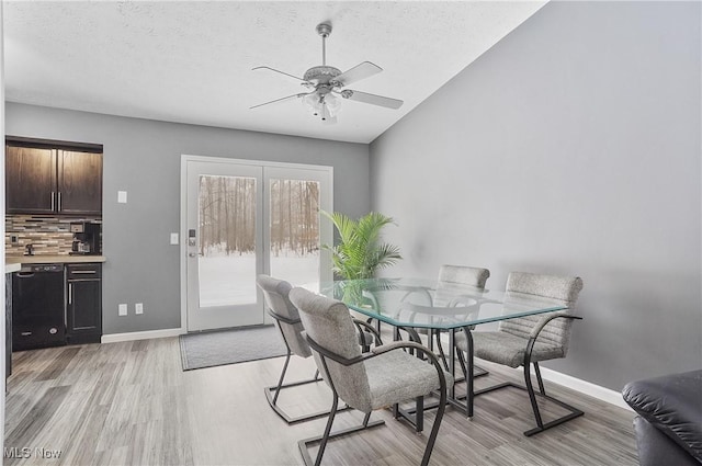 dining area featuring a textured ceiling, light hardwood / wood-style flooring, vaulted ceiling, and ceiling fan