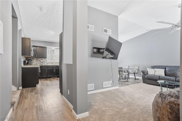 living room featuring ceiling fan, light hardwood / wood-style flooring, and vaulted ceiling