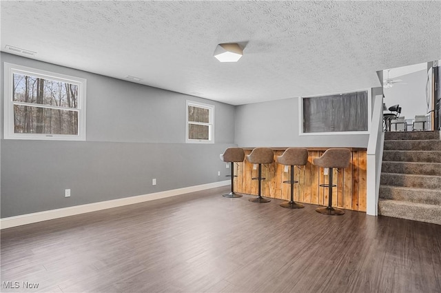 interior space featuring dark wood-type flooring, bar area, and a textured ceiling