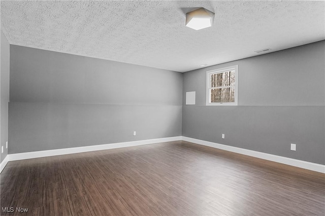 unfurnished room with a textured ceiling and dark hardwood / wood-style flooring