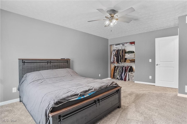 carpeted bedroom with ceiling fan, a textured ceiling, and a closet