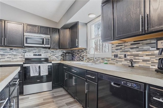 kitchen with appliances with stainless steel finishes, sink, dark brown cabinetry, backsplash, and vaulted ceiling