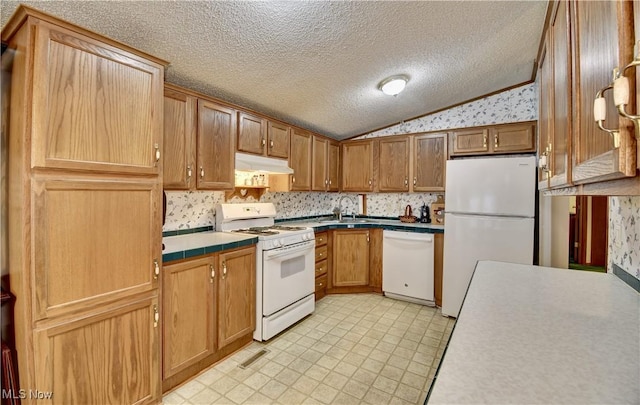 kitchen with sink, white appliances, lofted ceiling, and a textured ceiling