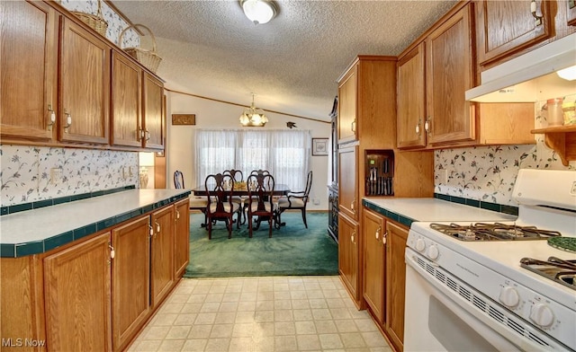 kitchen featuring a notable chandelier, a textured ceiling, hanging light fixtures, white range with gas stovetop, and lofted ceiling