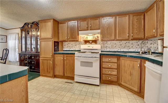 kitchen with sink, white appliances, a textured ceiling, and tile countertops