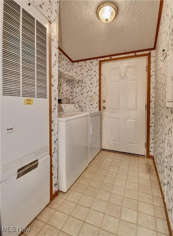 washroom with a textured ceiling and washing machine and dryer