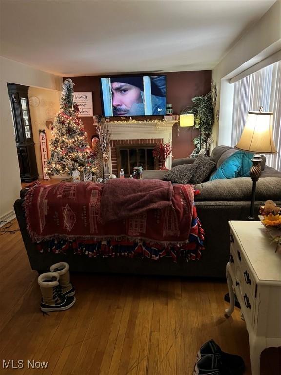 living room with wood-type flooring and a brick fireplace