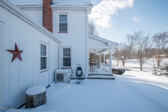 snow covered back of property featuring ac unit and a porch