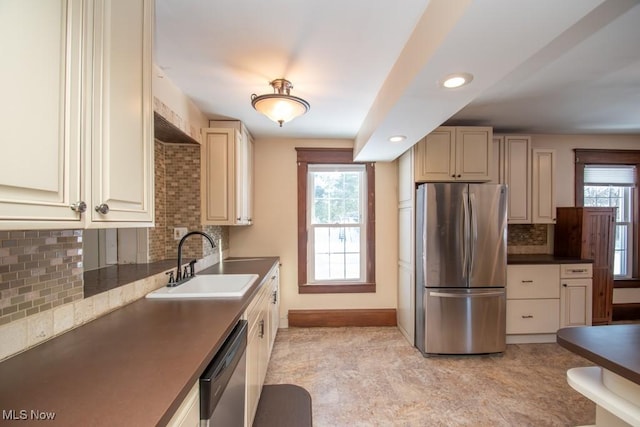 kitchen with sink, cream cabinets, appliances with stainless steel finishes, and tasteful backsplash