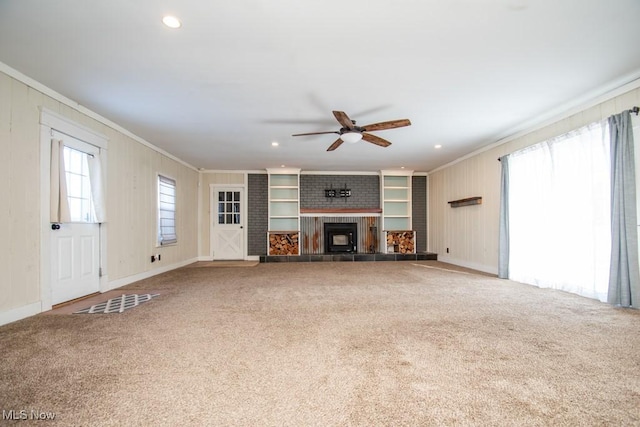 unfurnished living room featuring plenty of natural light, carpet, ornamental molding, and a fireplace