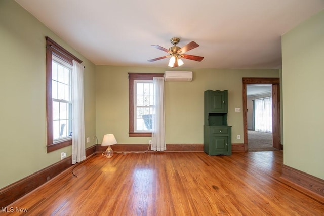 spare room with ceiling fan, a wealth of natural light, light hardwood / wood-style floors, and a wall unit AC