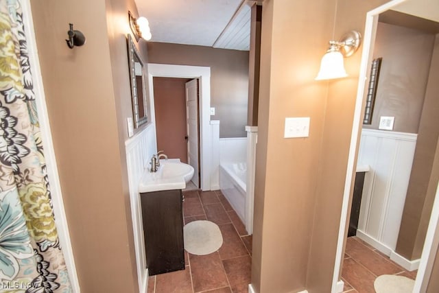 bathroom with a tub to relax in, tile patterned floors, and vanity