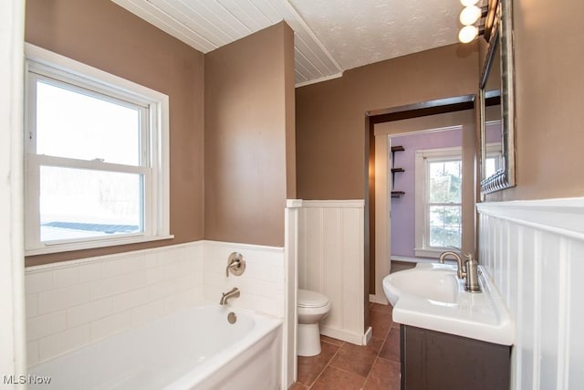 bathroom featuring tile patterned floors, a textured ceiling, toilet, vanity, and a washtub