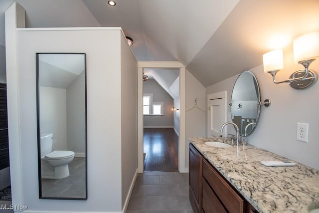 bathroom with tile patterned floors, toilet, vanity, and vaulted ceiling