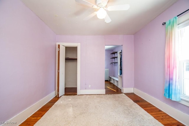 bedroom with a closet, ceiling fan, radiator, and dark hardwood / wood-style floors