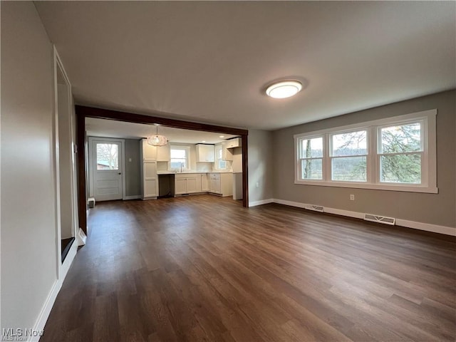 unfurnished living room featuring dark wood-type flooring and sink