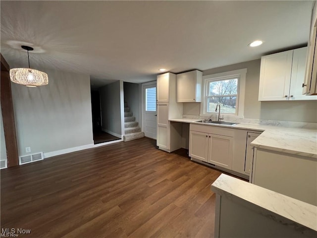 kitchen featuring decorative light fixtures, sink, white cabinets, dark wood-type flooring, and light stone countertops