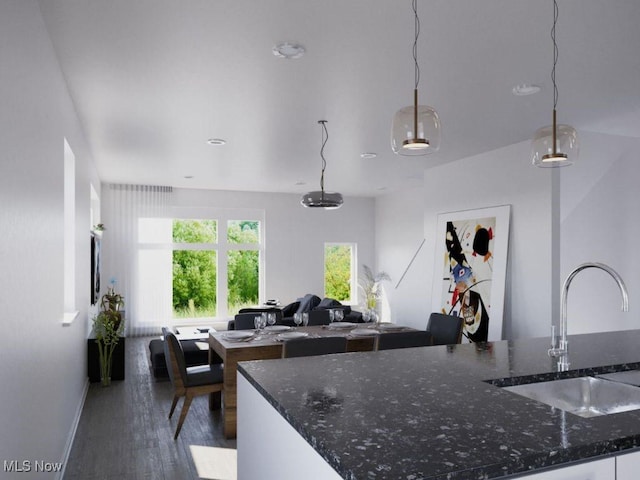 kitchen with sink, dark stone countertops, pendant lighting, and dark wood-type flooring