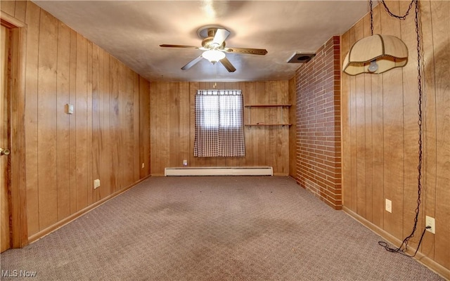 carpeted empty room with ceiling fan, a baseboard heating unit, and wood walls