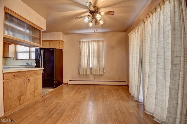 kitchen with a baseboard radiator, tasteful backsplash, black fridge, light wood-type flooring, and ceiling fan