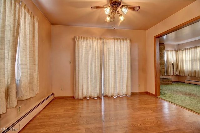 empty room with baseboard heating, light hardwood / wood-style floors, and ceiling fan