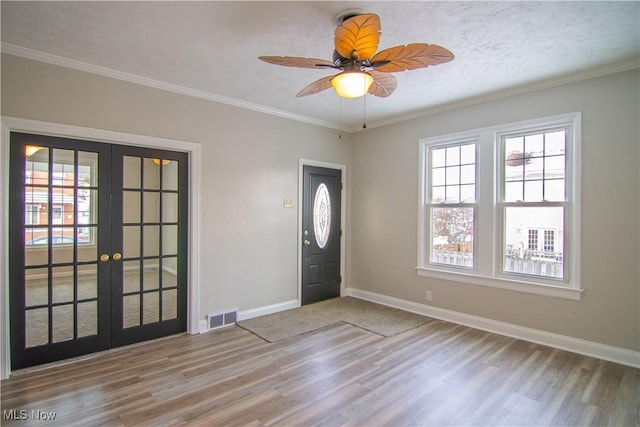 entrance foyer featuring ornamental molding, hardwood / wood-style flooring, a textured ceiling, and french doors