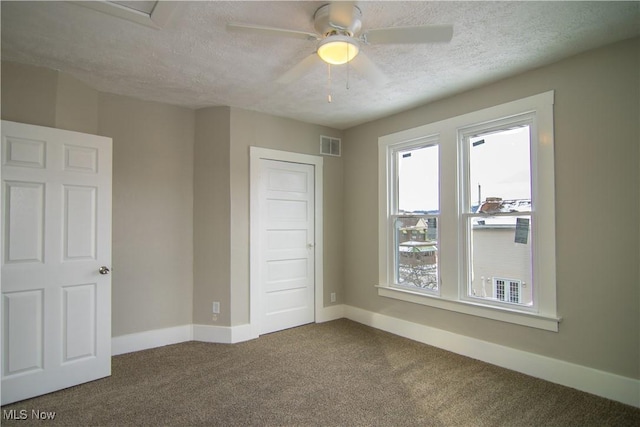 unfurnished bedroom with a closet, ceiling fan, carpet, and a textured ceiling