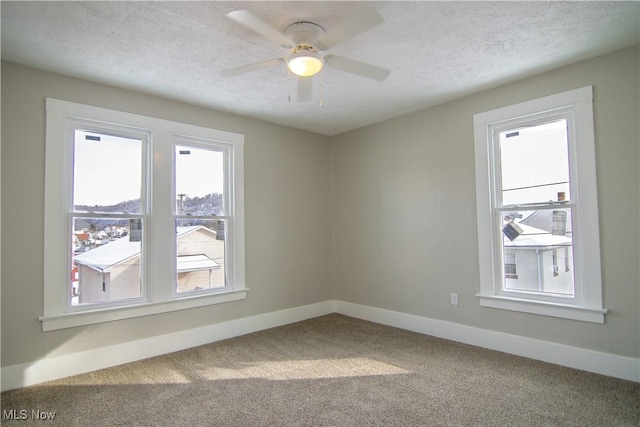 unfurnished room with a textured ceiling, carpet flooring, and ceiling fan