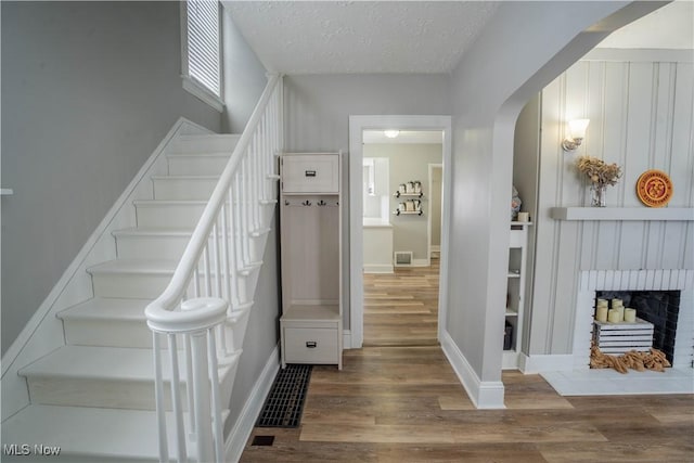 stairway with a fireplace, hardwood / wood-style floors, a textured ceiling, and built in features