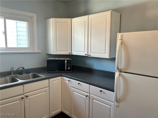 kitchen with sink, white refrigerator, and white cabinetry