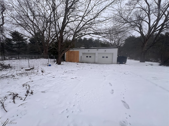 yard layered in snow with a garage and an outdoor structure