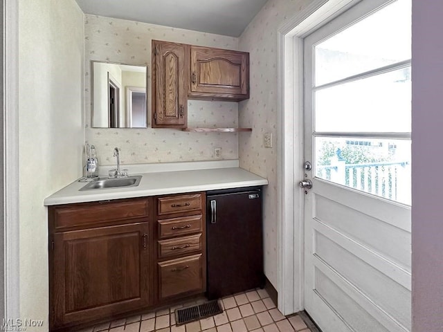 kitchen with sink, light tile patterned floors, and fridge