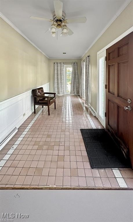 tiled entryway featuring ceiling fan and crown molding