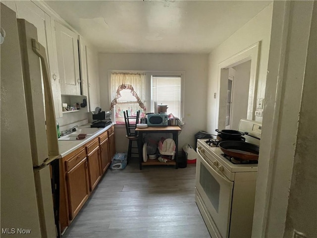 kitchen with sink, light hardwood / wood-style floors, refrigerator, and white gas range oven