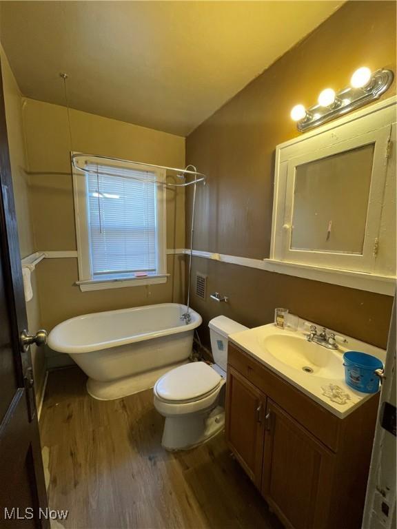 bathroom featuring hardwood / wood-style flooring, toilet, vanity, and a bathing tub