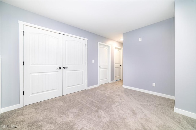 unfurnished bedroom with light colored carpet and a closet