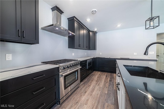 kitchen with hanging light fixtures, dark hardwood / wood-style flooring, wall chimney exhaust hood, appliances with stainless steel finishes, and light stone counters