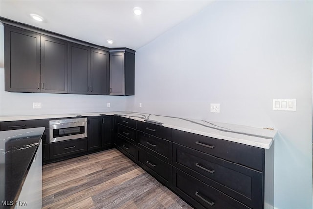 kitchen with hardwood / wood-style flooring and light stone counters