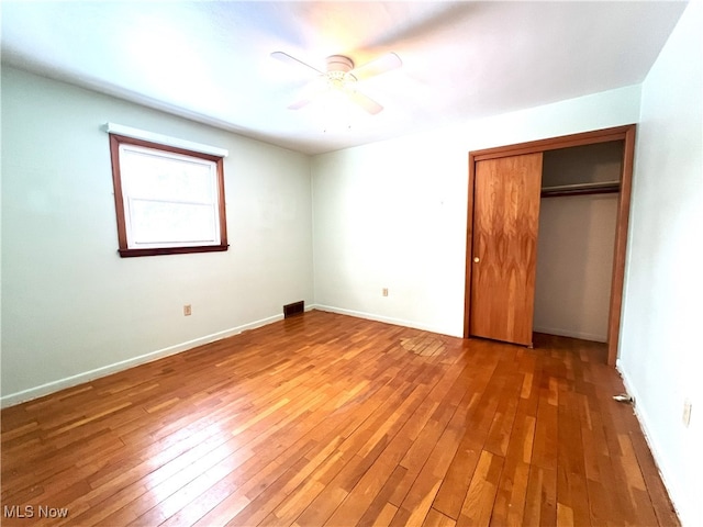 unfurnished bedroom with ceiling fan, wood-type flooring, and a closet